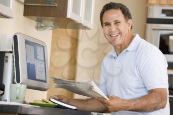 Royalty Free Photo of a Man at a Computer With a Newspaper