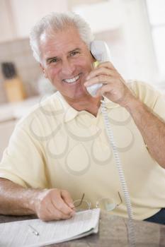 Royalty Free Photo of a Man on the Telephone With the Paper in Front of Him