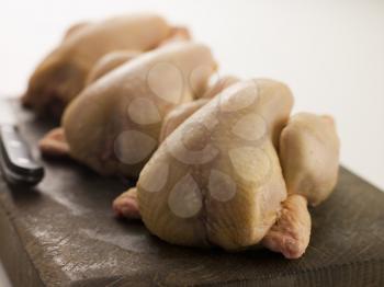 Royalty Free Photo of Three Whole Poussins on a Chopping Board
