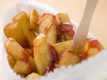 Royalty Free Photo of Chip Shop Chips in a Bag With a Wooden Fork and Tomato Ketchup