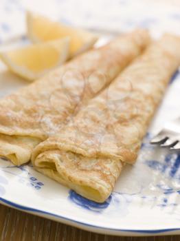 Royalty Free Photo of a Plate of Folded Pancakes Lemon and Sugar