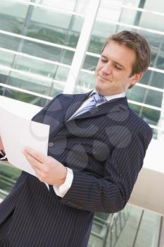Royalty Free Photo of a Man Looking at Paperwork Outside