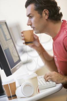 Royalty Free Photo of a Man at a Computer With Many Cups of Coffee Beside Him