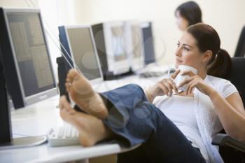 Royalty Free Photo of a Woman at Her Desk With Her Feet Up Drinking Coffee