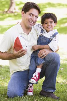 Royalty Free Photo of a Man and Boy Outside With a Football