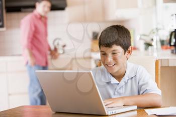 Royalty Free Photo of a Boy With a Laptop in the Kitchen