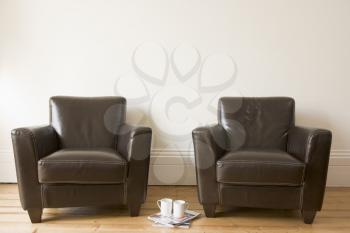 Royalty Free Photo of Two Chairs With Coffee Mugs and Magazines Betweeen Them