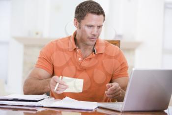 Royalty Free Photo of a Man in a Dining Room With a Laptop and Paperwork