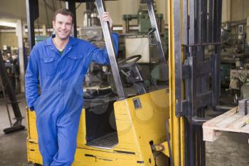 Royalty Free Photo of a Warehouse Worker Beside a Forklift