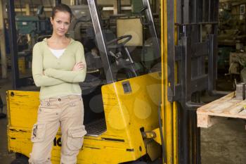 Royalty Free Photo of a Female Warehouse Worker Beside a Forklift