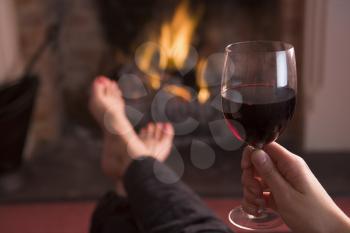 Royalty Free Photo of a Person With Wine Beside the Fire