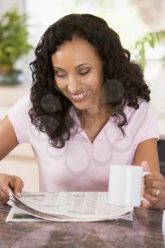 Royalty Free Photo of a Woman Reading a Paper and Holding a Coffee Mug