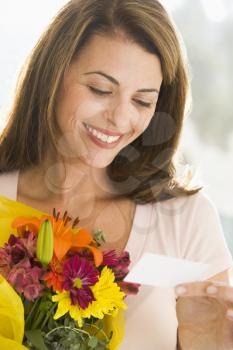 Royalty Free Photo of a Woman With Flowers Reading the Card