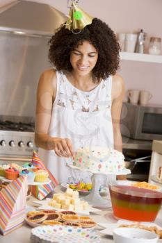 Royalty Free Photo of a Woman Decorating a Cake and Wearing a Party Hat