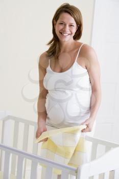 Royalty Free Photo of a Pregnant Woman Beside a Baby Crib