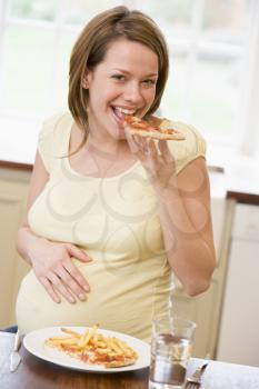 Royalty Free Photo of a Pregnant Woman With French Fries and Pizza