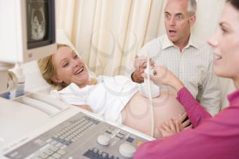 Royalty Free Photo of a Woman Getting an Ultrasound With Her Surprised Husband