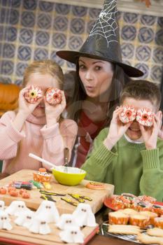 Royalty Free Photo of a Woman in a Witches Hat With Two Children Making Halloween Treats