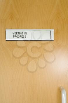 Royalty Free Photo of a Meeting in Progress Sign on a Door