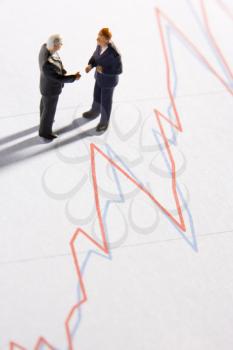 Royalty Free Photo of Businessman Figurines Shaking Hands By a Graph