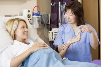 Royalty Free Photo of a Nurse Taking a Pregnant Woman's Temperature