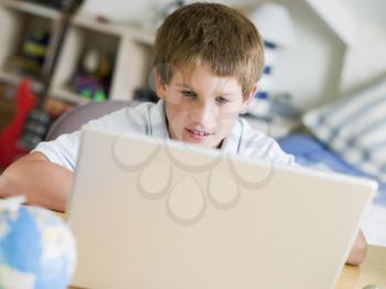 Royalty Free Photo of a Young Boy With a Laptop in His Bedroom