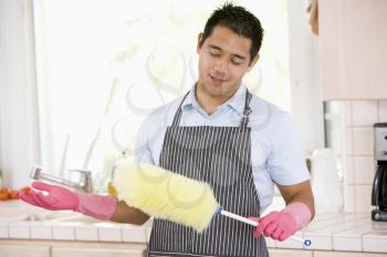 Royalty Free Photo of a Man Holding a Duster and Wearing Rubber Gloves