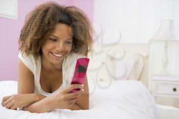 Royalty Free Photo of a Teenage Girl on a Bed With a Cellphone