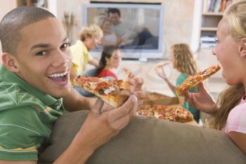 Royalty Free Photo of Teens Watching TV and Eating Pizzas