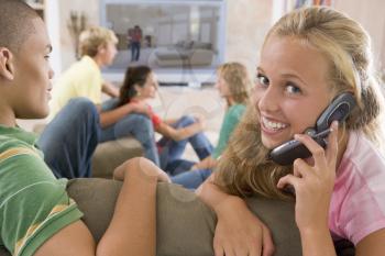 Royalty Free Photo of Teens Watching TV and One Using a Cellphone