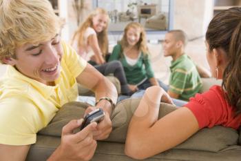 Royalty Free Photo of Teens Watching TV and One Boy on a Cellphone