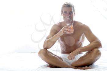 Royalty Free Photo of a Man Drinking Juice on a Bed
