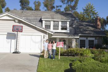 Royalty Free Photo of a Family With a Real Estate Sign on Their Property