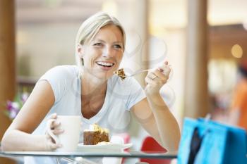 Royalty Free Photo of a Woman Eating a Piece of Cake at a Mall