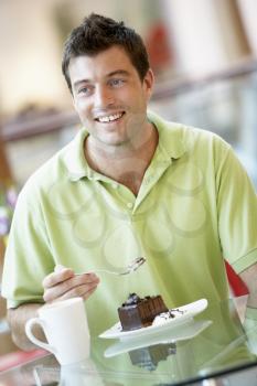 Royalty Free Photo of a Man Eating Cake at a Mall