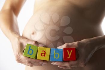 Royalty Free Photo of a Pregnant Woman Holding Blocks Spelling Baby