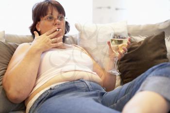 Royalty Free Photo of an Overweight Woman on the Couch with Wine and a Cigarette