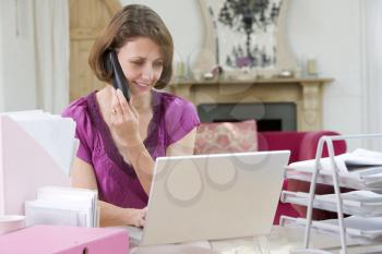 Royalty Free Photo of a Woman With a Laptop Talking on the Telephone