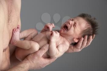 Royalty Free Photo of a Baby Crying in His Father's Hands