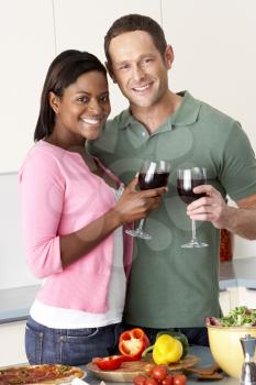 Royalty Free Photo of a Couple Enjoying Wine While Preparing a Meal