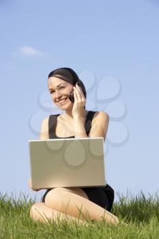 Royalty Free Photo of a Woman Outside With a Laptop and a Cellphone