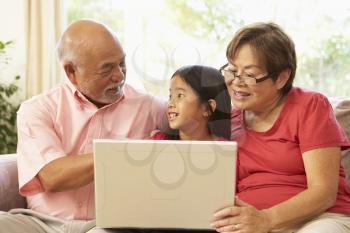 Royalty Free Photo of Grandparents With the Granddaughter Looking at a Laptop