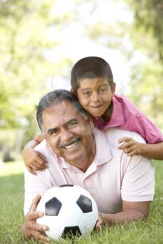 Royalty Free Photo of a Grandfather and Grandson on the Ground With a Soccer Ball