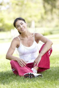 Royalty Free Photo of a Woman in Exercise Clothes Sitting on Grass