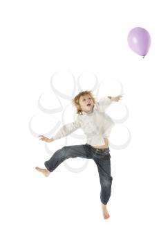 Young Boy Jumping With Balloon In Studio