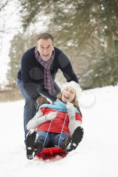Senior Couple Sledging Through Snowy Woodland