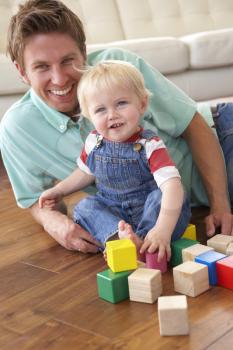 Father And Son Playing With Coloured Blocks At Home
