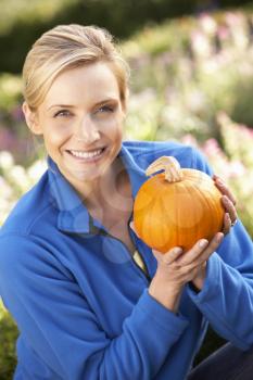 Young woman posing with pumpkin in garden