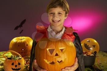 Halloween party with a boy child holding carved pumpkin