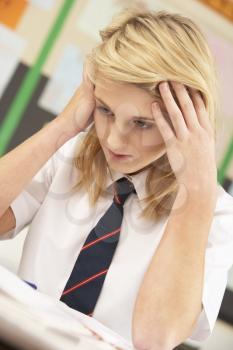 Stressed Female Teenage Student Studying In Classroom
